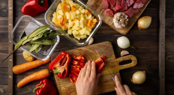 Przygotowania do pysznego **cheat meal**: krojenie papryki, mięso, ziemniaki, marchew, cebula, czosnek i liście laurowe.