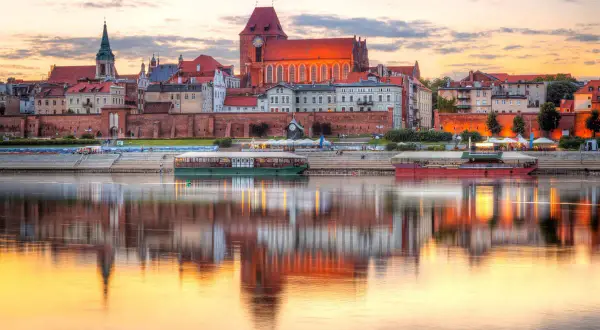 Zachód słońca nad Wisłą, odbijający w wodzie zabytkowe kamienice i katedrę. Piękne stare miasta w Polsce.