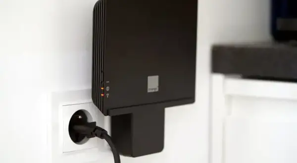 Czarny router Orange, model funbox 6, podłączony do gniazdka elektrycznego.