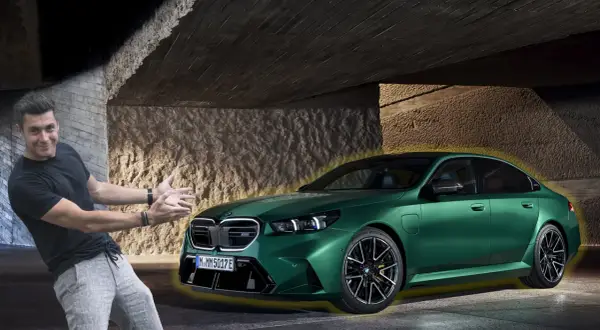 Mężczyzna z entuzjazmem prezentuje lśniące, zielone bmw g90 pod betonowym zadaszeniem.