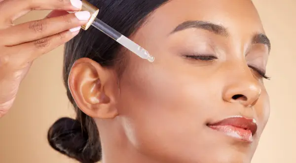 Delikatna aplikacja serum z kwasem salicylowym i retinolem na twarz. Skóra staje się gładka i promienna.