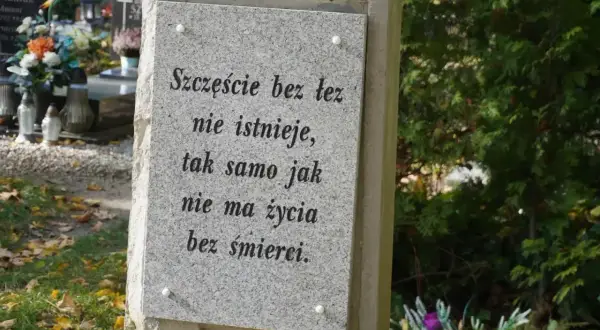 Kamienna płyta na grobie urnowym z napisem "Szczęście bez łez nie istnieje, tak samo jak nie ma życia bez śmierci".