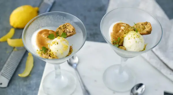 Två glas med citronsorbet, maräng och biscotti. En perfekt limoncello dessert för en solig dag.