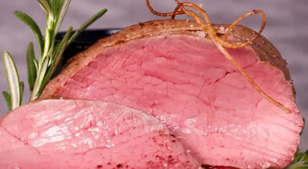 Saftiges Rinderfilet im Backofen, perfekt rosa gebraten, mit Rosmarin und einer dekorativen Schnur aus Bratensaft.