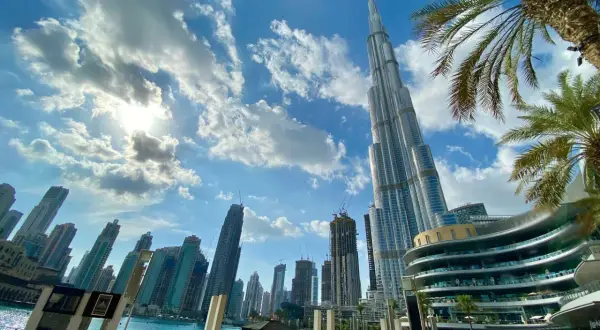 Burj Khalifa i inne drapacze chmur w Dubaju. Słońce przebija się przez chmury. Warto zabrać do Dubaju okulary przeciwsłoneczne i lekki ubiór.