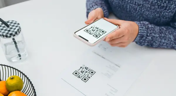 Une personne scanne un QR code sur un document avec son téléphone, peut-être pour activer une carte eSIM Bouygues.