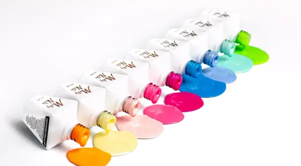 Kolorowe lakiery Molly Nails wylewają się z buteleczek, tworząc tęczowe plamy. Hema free co to znaczy? To bezpieczeństwo dla Twoich paznokci!