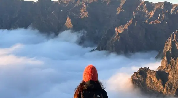 Widok na góry i morze chmur, jak na La Isla Bonita po polsku. Słońce oświetla skaliste szczyty.