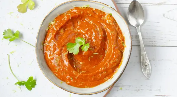 Un tazón de cremosa salsa chipotle, adornado con cilantro fresco y ralladura de lima, listo para acompañar tus platillos.