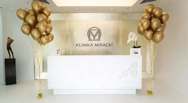 Recepcja kliniki z bukietami złotych balonów i logo.