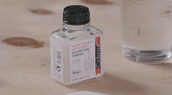 Bouteille de diluant Cobra pour peinture acrylique à base d'eau, sur fond de bois.