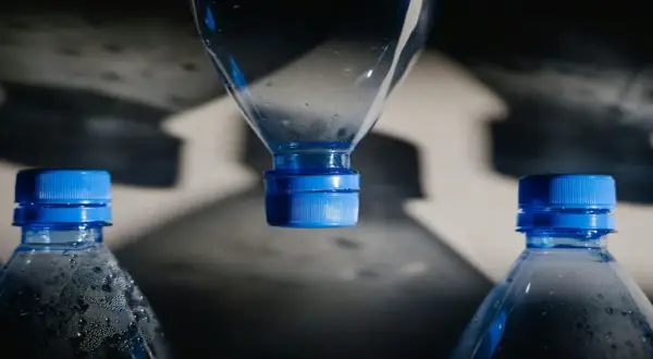 Bouteilles d'eau en plastique avec bouchons bleus. L'eau de Mont Roucous, une source d'eau naturelle, peut présenter un danger si elle est mal conservée.