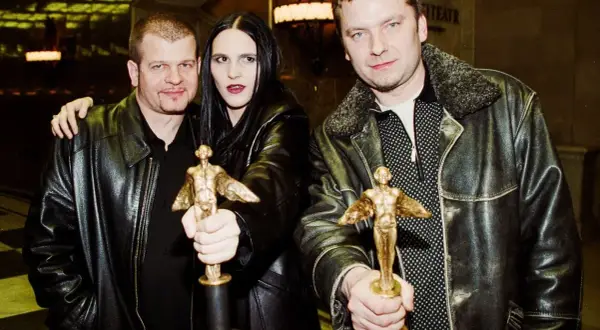 Trzech laureatów Fryderyków pozuje z nagrodami. Mężczyzna po lewej obejmuje kobietę, która trzyma statuetkę.