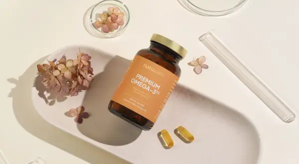 Butelka z napisem "PREMIUM OMEGA-3TG" i dwie kapsułki. Idealne wsparcie dla rozwoju mózgu i serca w ciąży.