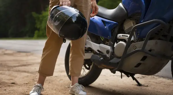 Osoba trzyma kask obok niebieskiego motocykla. Zastanawiasz się, czy można holować motocykl?