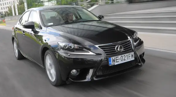 Czarny Lexus IS, doskonały wybór wśród lexusów używanych, pędzi ulicą. Kierowca wpatrzony w drogę.