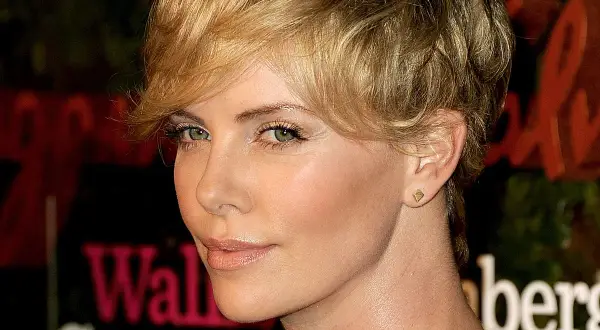 Charlize Theron w fryzurze pixie, która dodaje objętości cienkim włosom, z subtelnym makijażem i złotą biżuterią.