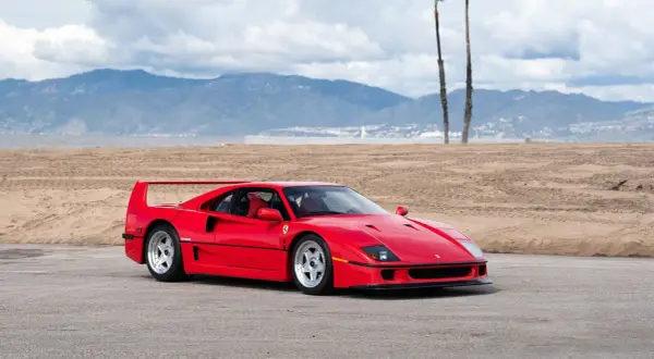 Czerwone Ferrari f40 na tle plaży i gór. Ikona motoryzacji gotowa do jazdy.