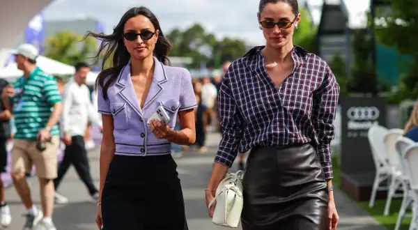 Rebecca Donaldson y su amiga pasean con estilo. Una lleva un blazer lila y falda negra, la otra, camisa a cuadros y falda de cuero.