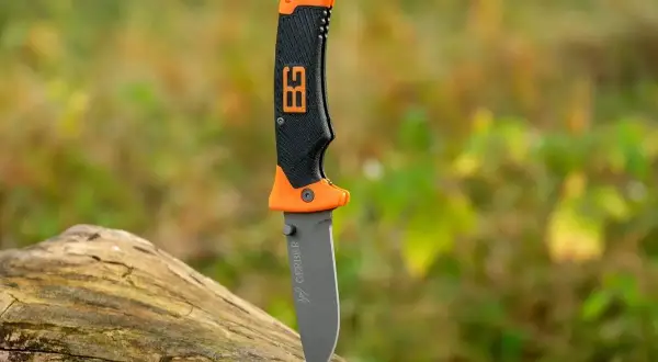 Cuchillo de supervivencia Gerber con mango naranja y negro, listo para la aventura en la naturaleza.
