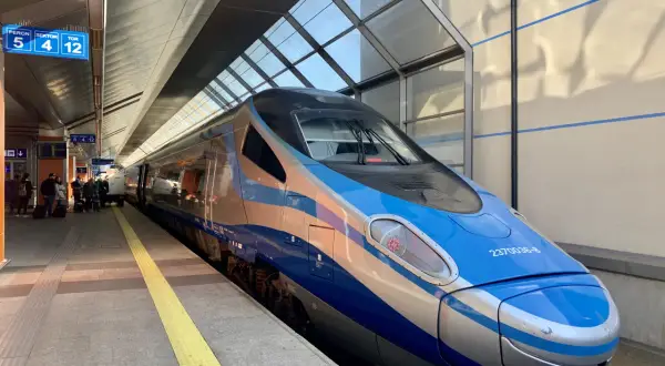 Nowoczesny pociąg InterCity w kolorach niebieskim i srebrnym stoi na peronie.