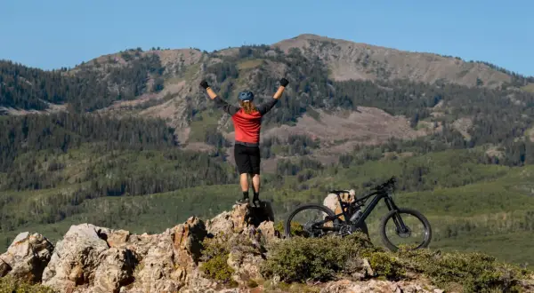 Ciclista celebra cima de montaña, listo para un camino de Santiago en bici con niños.