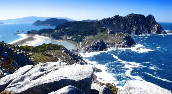 Paisaje costero con rocas, mar azul y una playa de arena blanca. Así es donde está Galicia, un paraíso natural.