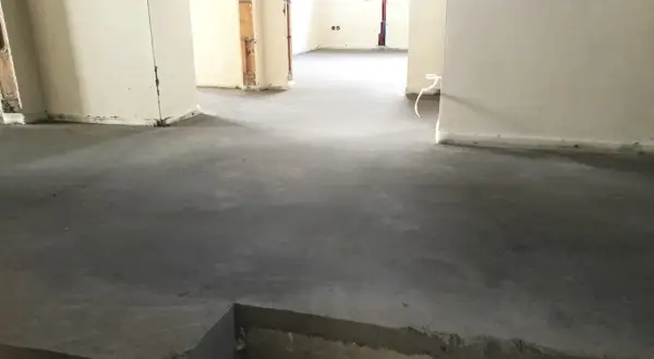 Surowy, betonowy jastrych co to? To podłoga gotowa na wykończenie. Widać fragmenty ścian i instalacji.