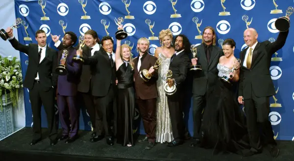 Die Besetzung von Lost feiert Emmy-Gewinne. Die Schauspieler posieren mit ihren Trophäen vor einem blauen Banner mit dem CBS-Logo.