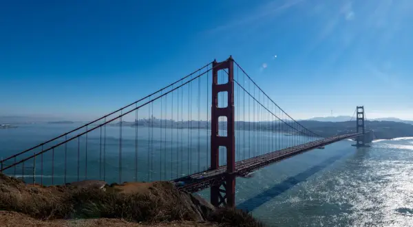 Ikoniczny most w San Francisco rozciąga się nad błękitną wodą, z miastem w oddali.