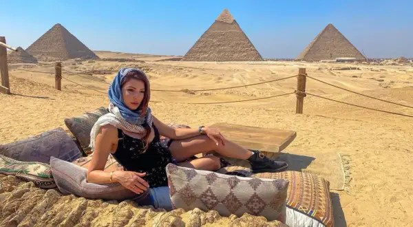 Mujer con velo descansa ante las pirámides de Giza. El sol brilla, un día perfecto, la mejor época para ir a Egipto.