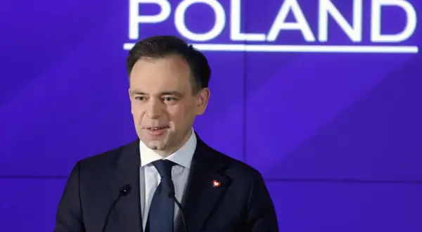 Mężczyzna w garniturze przemawia na tle napisu "POLAND". Dyskutuje o przyszłości cyfrowej gospodarki i potencjalnym podatku cyfrowym.
