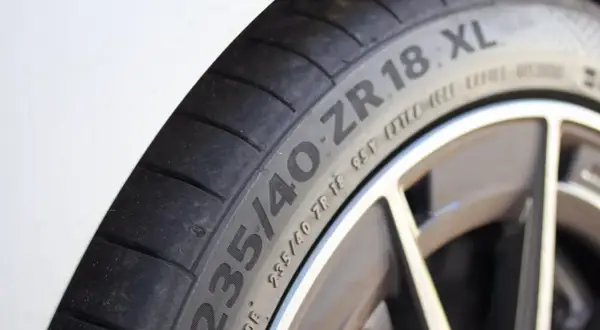 Gros plan sur un pneu de voiture avec l'inscription "235/40 ZR 18 XL", indiquant une capacité de charge renforcée pour une conduite sportive.