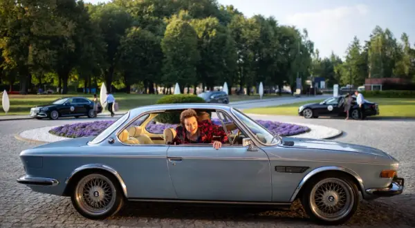 Uśmiechnięta kobieta w samochodzie przed hotelem z teściowie 2.