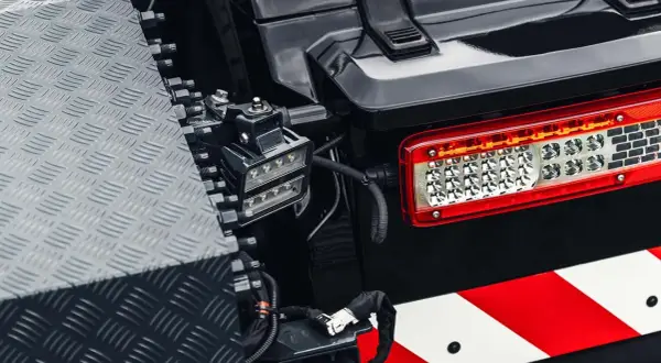 Feu arrière LED d'un véhicule tout-terrain, avec une bande réfléchissante rouge et blanche. Un projecteur auxiliaire est monté à proximité, conforme à la norme IP63.