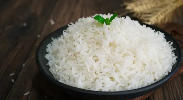 Un piatto di riso basmati, cotto alla perfezione, guarnito con una fogliolina di menta. La cottura ideale per un riso profumato.