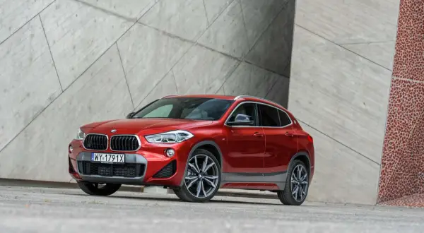 Czerwone BMW X2 na tle nowoczesnej architektury. Wiele osób szuka bmw x2 opinie przed zakupem.