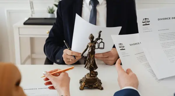Prawnik analizuje dokumenty rozwodowe, obok figurki Temidy. Zapewnienie sprawiedliwego podziału majątku.
