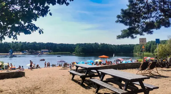 Słoneczny dzień nad jeziorem Średnim Turawa. Ludzie odpoczywają na plaży, kąpią się i pływają.