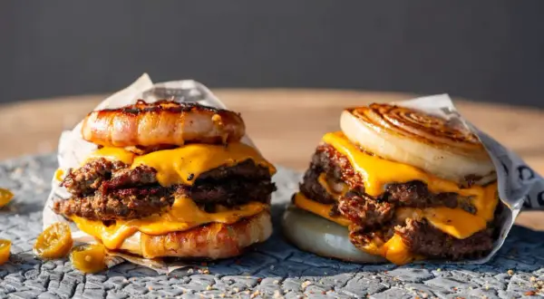Zwei saftige "Flying Dutchman Burger" mit doppelt Fleisch, geschmolzenem Käse und einer Zwiebel- bzw. Speckkrone.