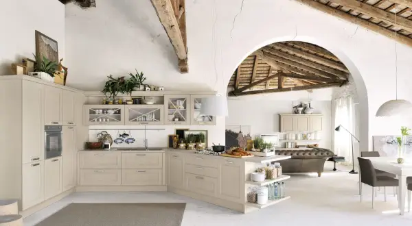 Jasna kuchnia shabby chic z drewnianymi belkami na suficie, wyspą i otwartą przestrzenią z sofą.