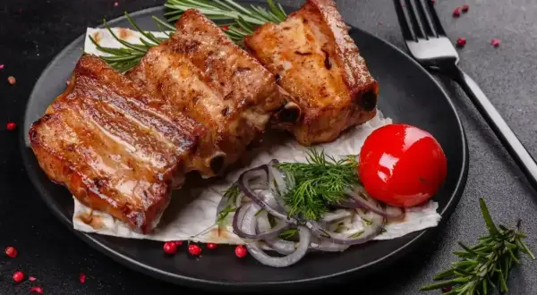 Soczyste żeberka w coli, podane z pomidorkiem, cebulą i rozmarynem. Idealne na obiad.