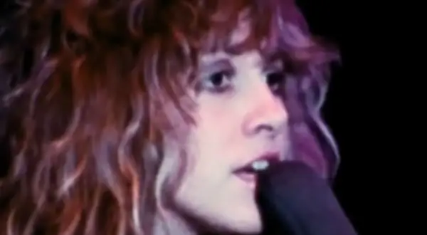 Stevie Nicks śpiewa "Dreams" Fleetwood Mac, jej charakterystyczne falujące włosy i intensywne spojrzenie.