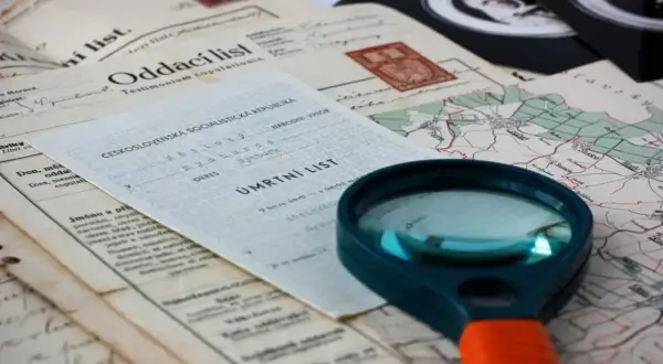 Loupe pour retrouver un acte de décès. Documents anciens, carte et loupe suggèrent une recherche généalogique.