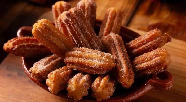Un piatto colmo di churros dorati, cosparsi di zucchero. Una deliziosa churros ricetta da gustare.