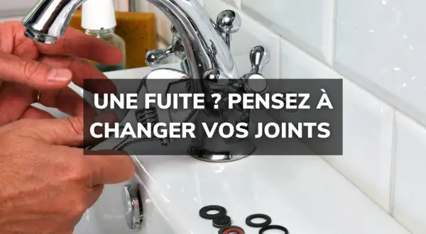 Main d'un bricoleur tenant une clé pour changer un joint de robinet. Des joints neufs sont disposés sur le lavabo.