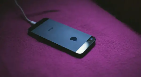 iPhone podłączony do ładowania. Dowiedz się, jak zmierzyć pojemność baterii, aby wiedzieć, jak długo telefon będzie działał.