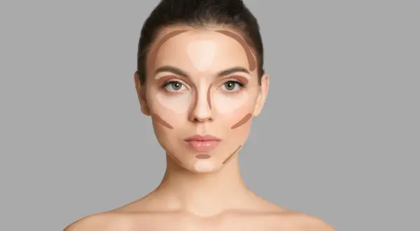 Modelka pokazuje, gdzie nakładać bronzer i rozświetlacz, by wymodelować twarz. Linie na policzkach, czole i nosie.