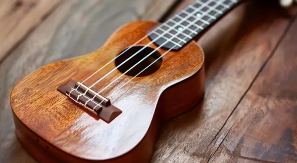 Drewniane ukulele na rustykalnym blacie. Idealne do nauki akordów "Can't Help Falling in Love".
