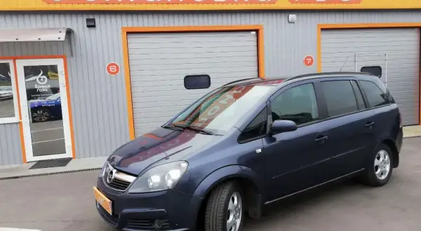 Opel Zafira 1.6 benzyna opinie: rodzinny van przed budynkiem z napisem "Установка ГБО".